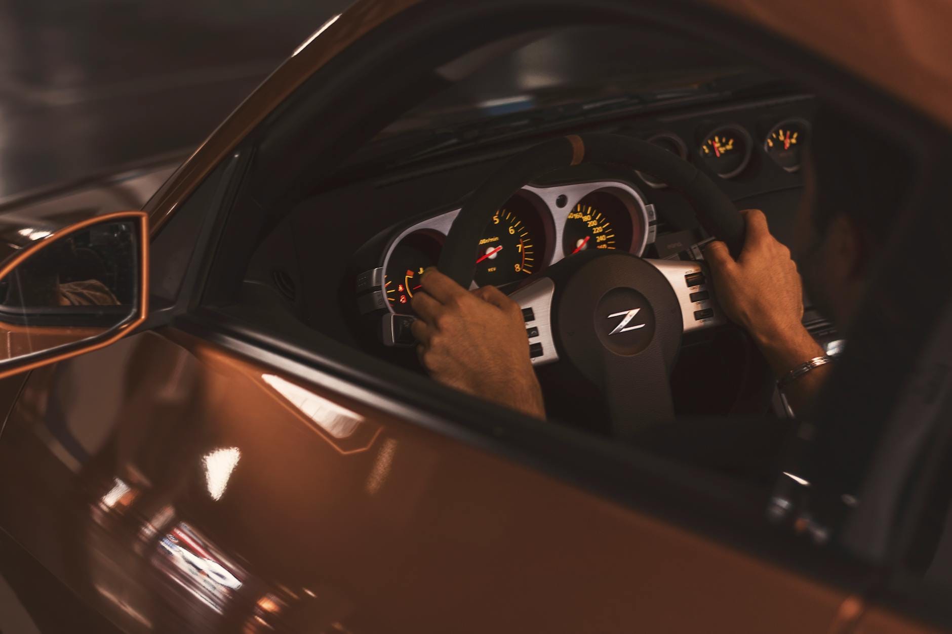 Kierowca trzymający kierownicę Nissana, widoczny sportowy zegar prędkości