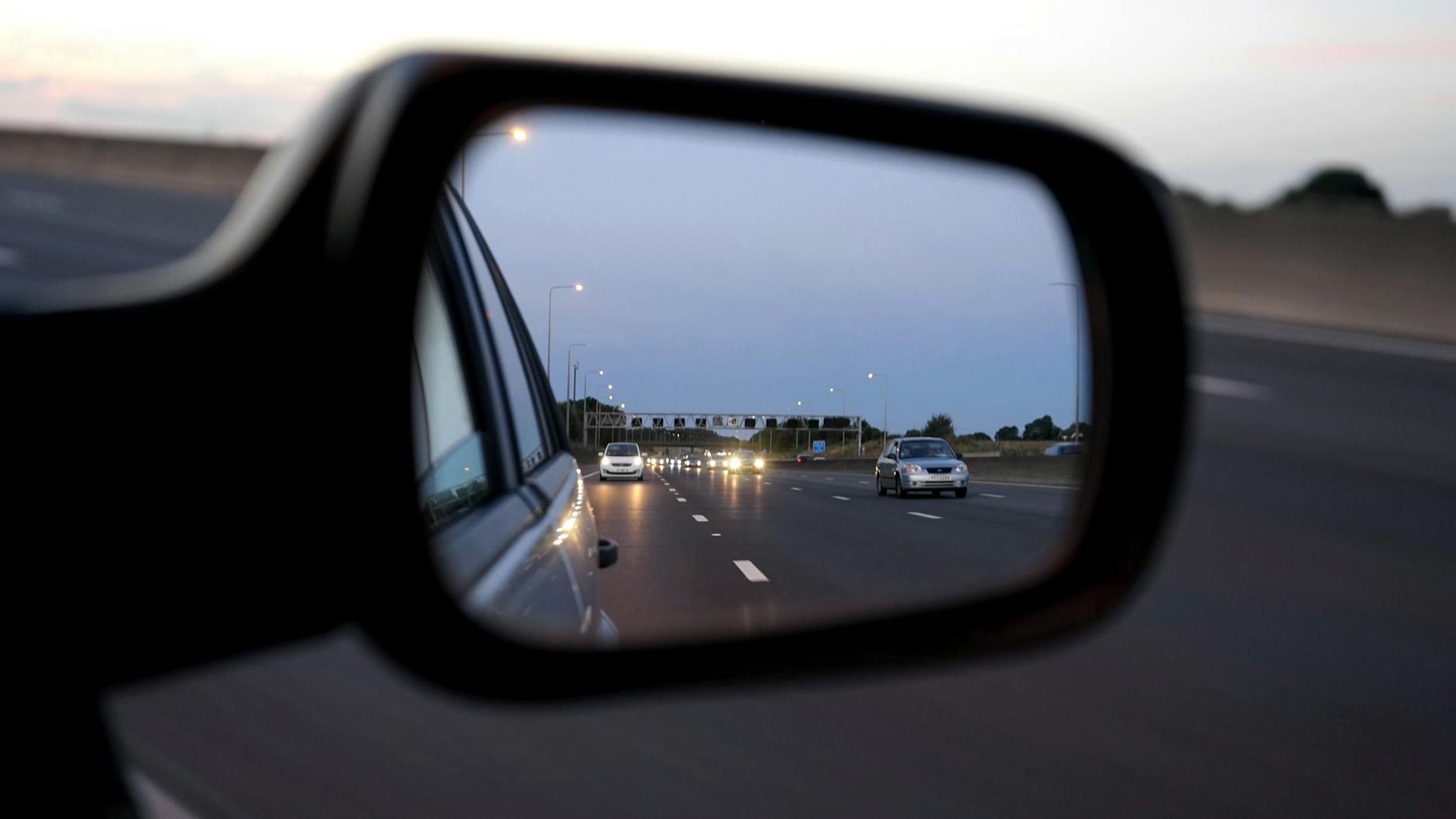 Samochody na autostradzie w lusterku bocznym o zmierzchu