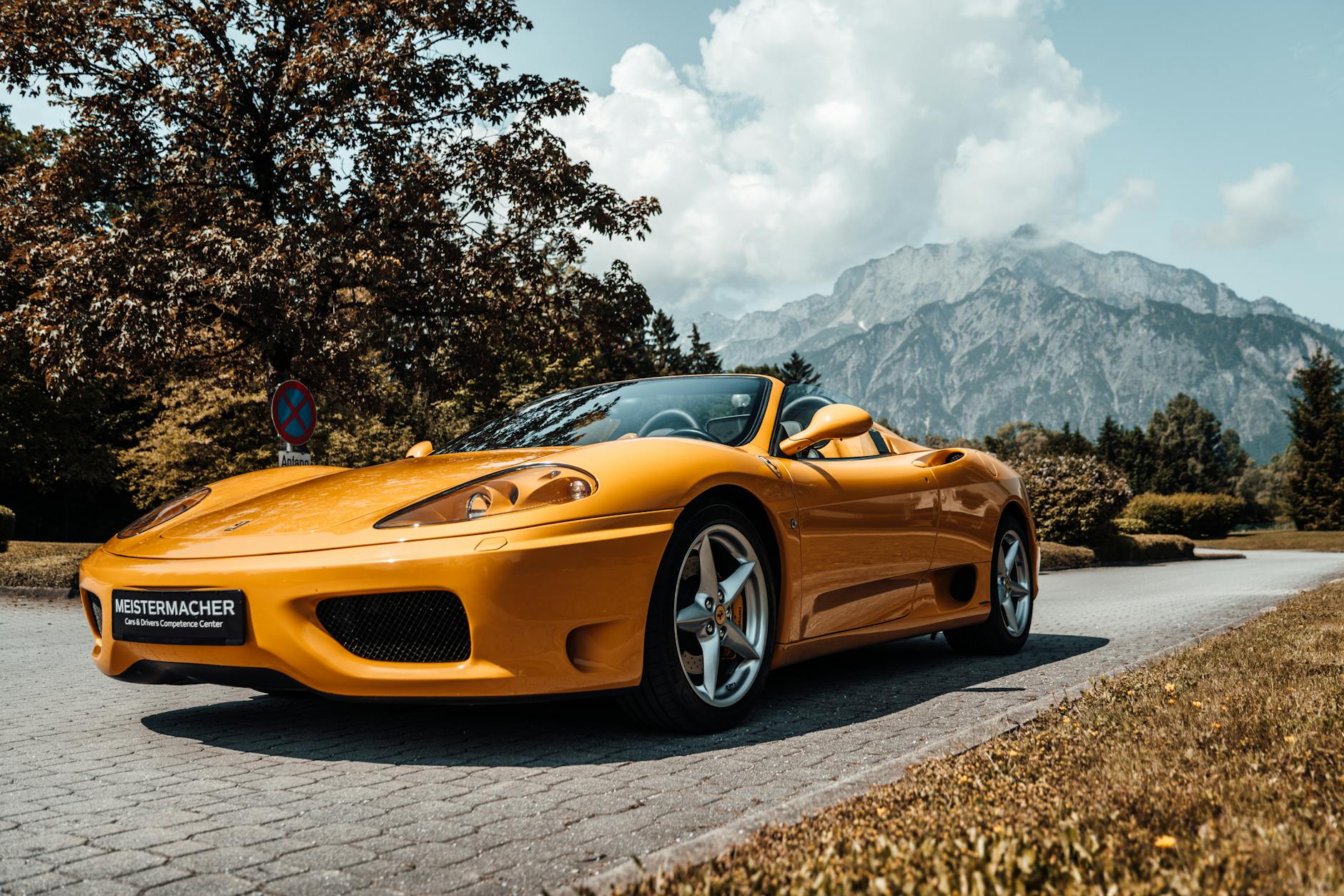 Żółty kabriolet sportowy jedzie górską drogą wśród alpejskich krajobrazów