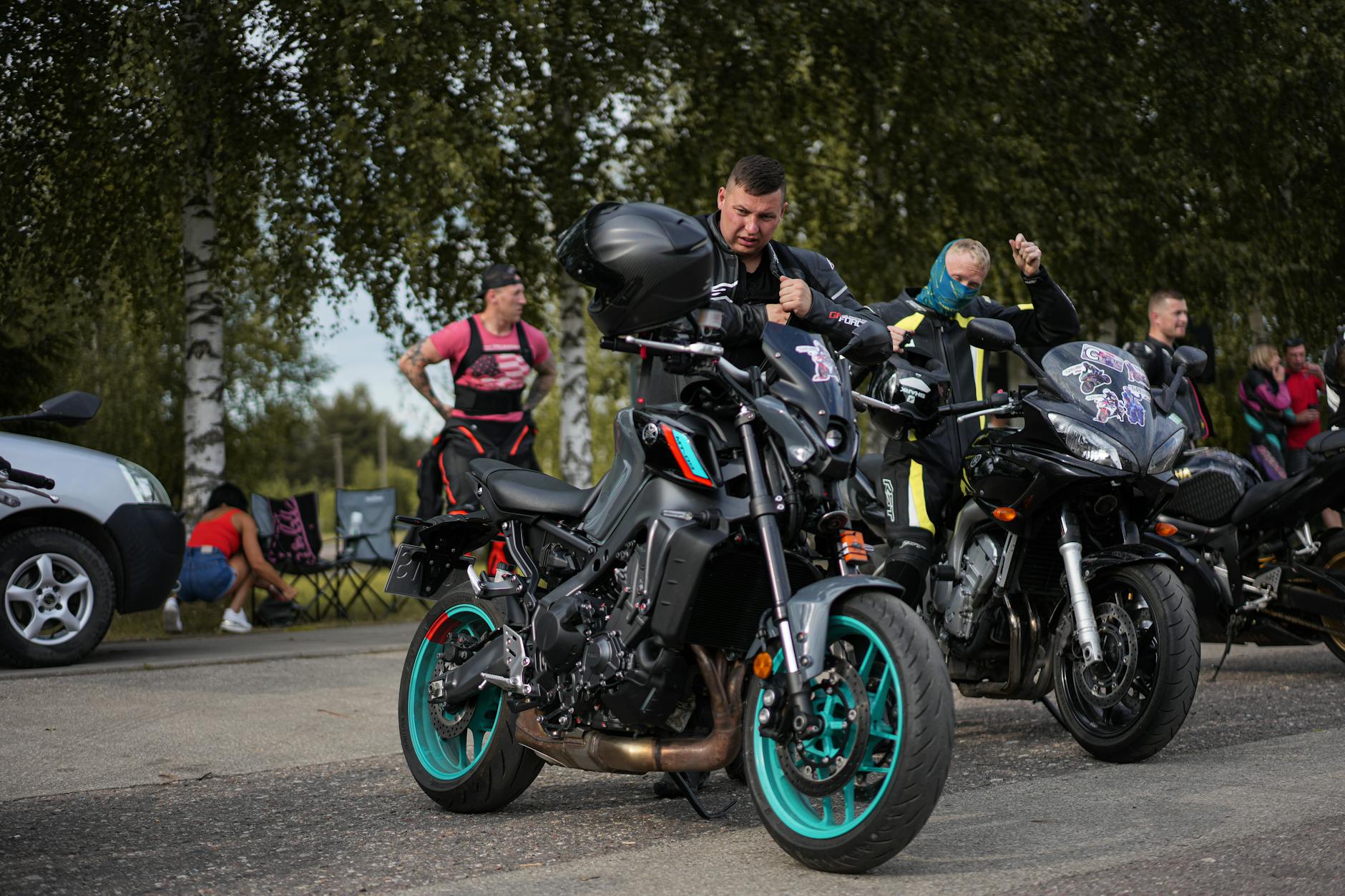 Motocykliści poprawiający ubrania przy motocyklach na słonecznym zlocie