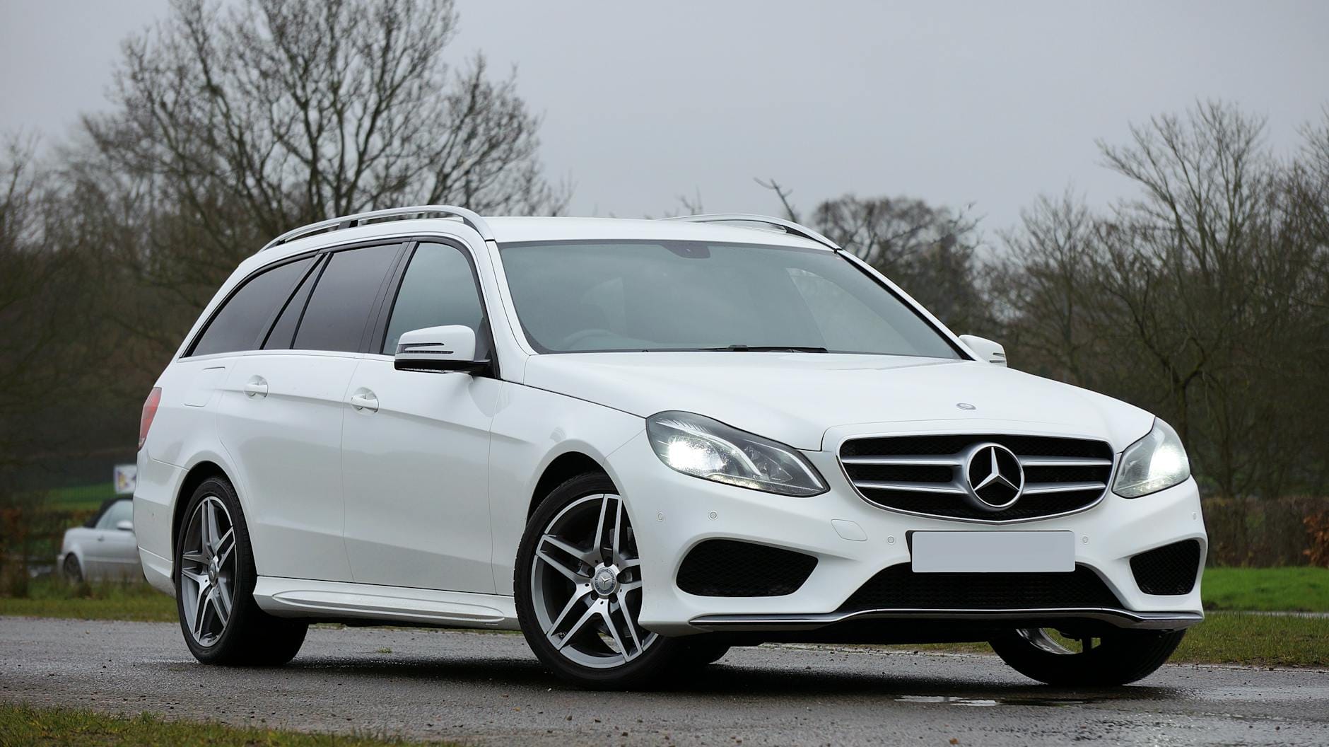 Białe sportowe kombi Mercedes E-Class jedzie drogą wśród zieleni
