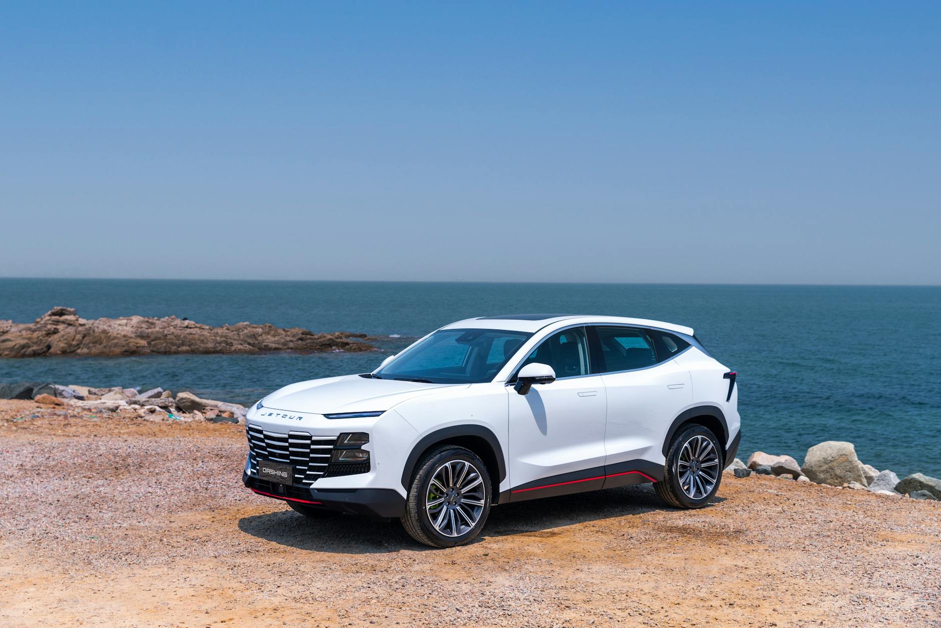 Biały elegancki SUV zaparkowany nad morzem w słoneczny dzień Biały elegancki SUV zaparkowany nad morzem w słoneczny dzień