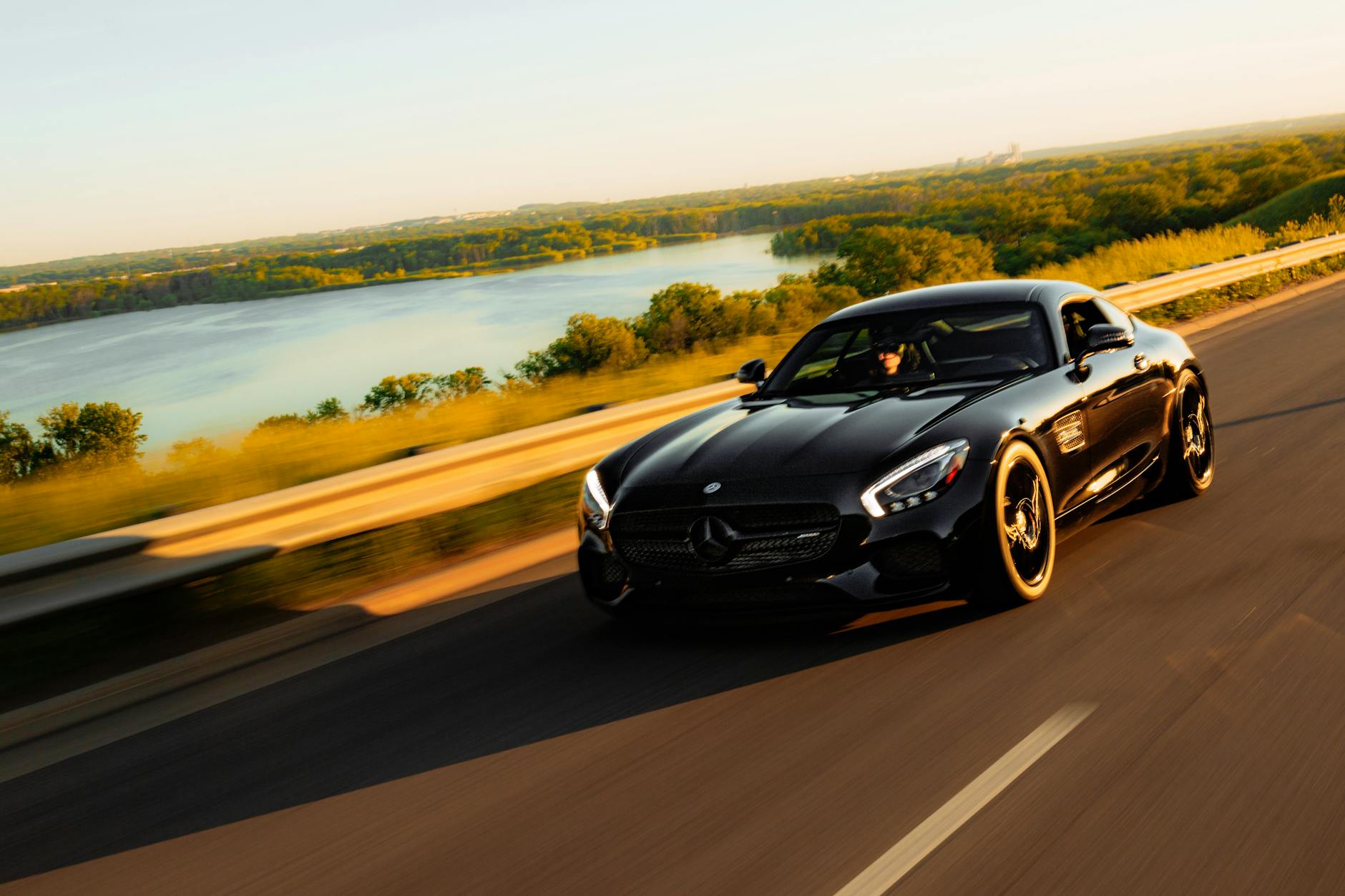 Czarny samochód Gran Turismo na malowniczej drodze nad jeziorem Czarny samochód Gran Turismo na malowniczej drodze nad jeziorem