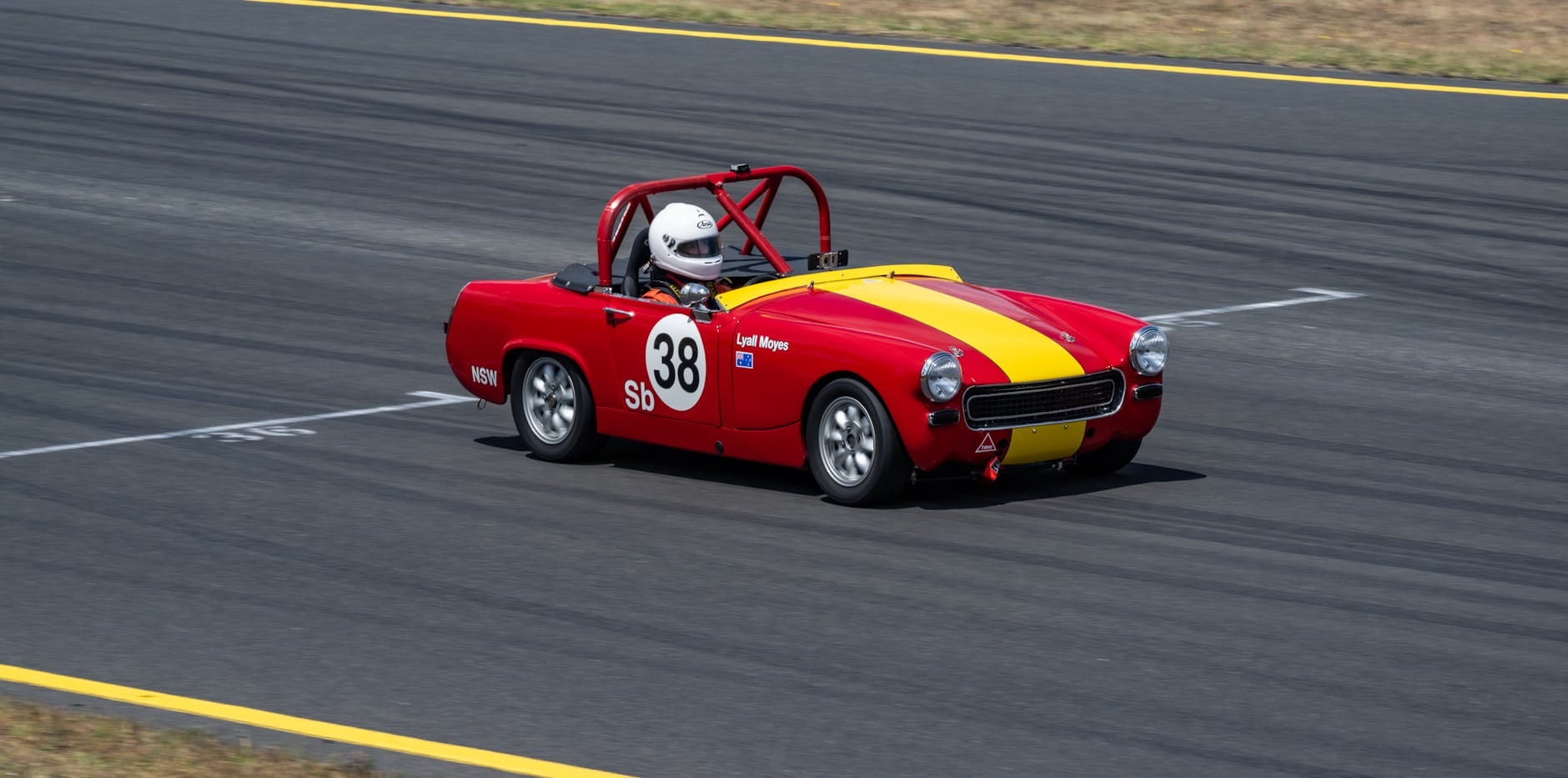 Czerwone klasyczne auto sportowe prowadzone po asfaltowym torze