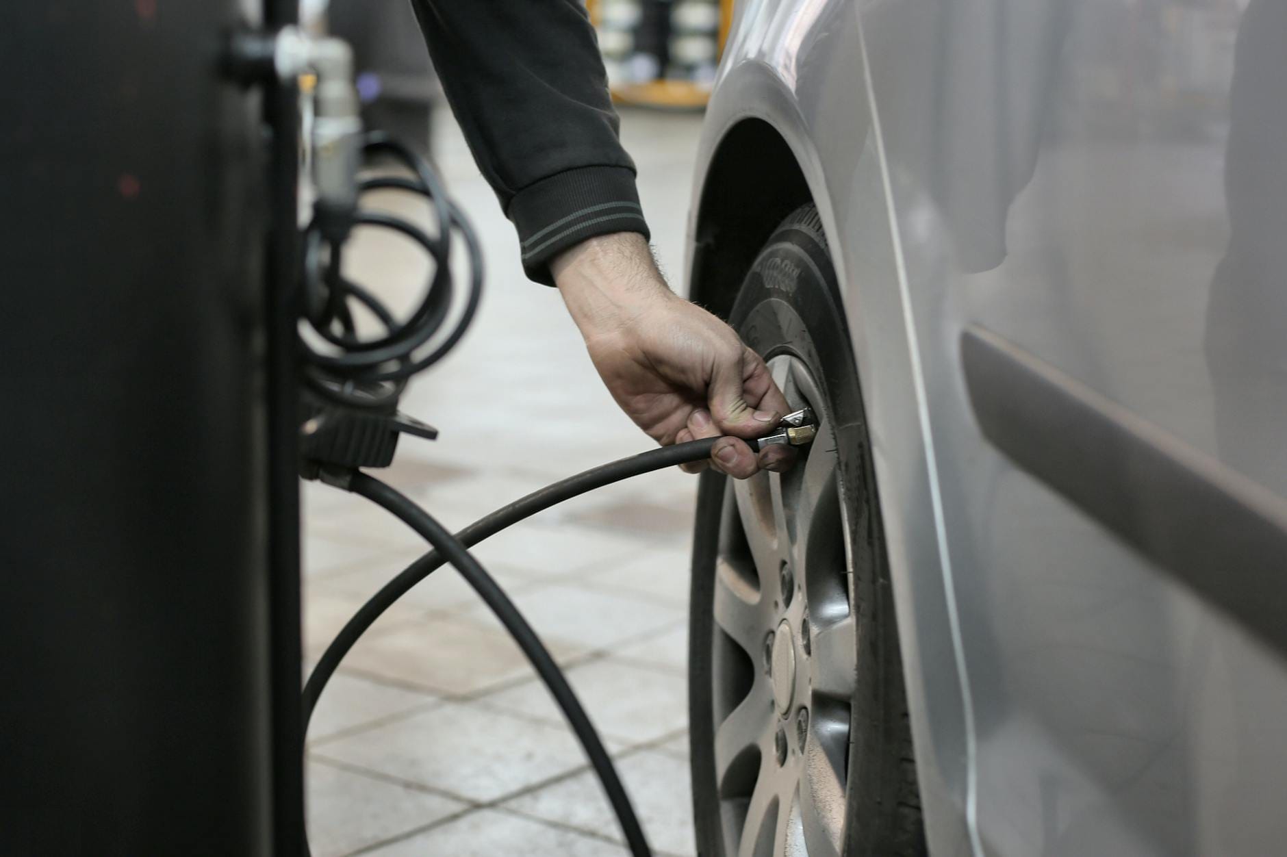 Mechanik dopompowuje oponę samochodu w warsztacie, sprawdzając ciśnienie