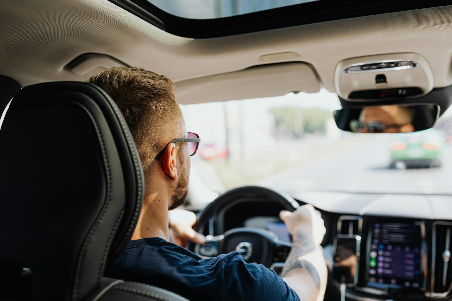 Mężczyzna prowadzi auto, widok z tyłu na kierownicę i deskę rozdzielczą