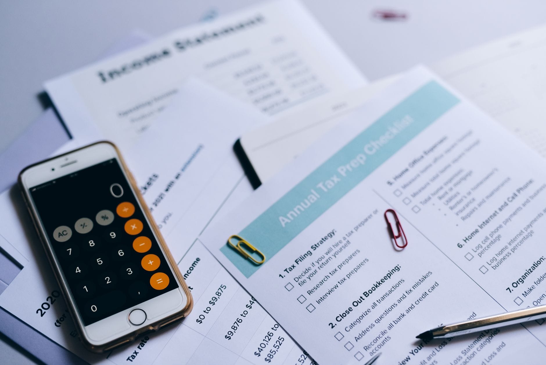 Dokumenty podatkowe z kalkulatorem w smartfonie i listą kontrolną