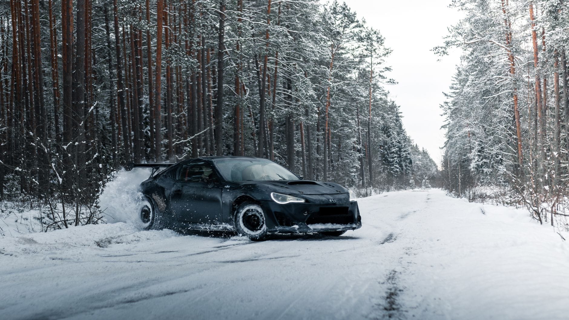 Sportowe auto w kontrolowanym poślizgu na ośnieżonej leśnej drodze